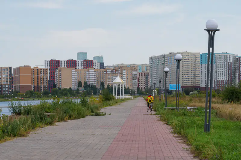 Курьер на велосипеде едет по набережной, Астана